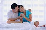 Couple sitting on bed, woman holding glass of milk