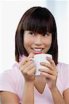 Young woman holding mug, smiling