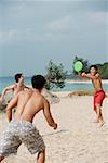 Three men on beach playing with Frisbee