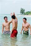 Three men standing waist deep in sea