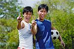 Two men looking at camera, making hand sign