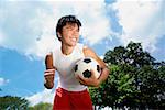 Jeune homme avec ballon de soccer, à la main dans un coup de poing, souriant
