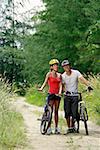 Couple Standing mit Fahrrädern, lächelnd in die Kamera