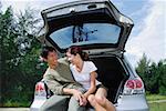 Couple sitting in boot of car