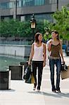 Two women walking side by side, carrying shopping bags