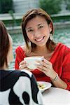 Women having coffee, one woman smiling at camera