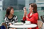 Deux femmes au café en plein air, à l'aide d'une caméra