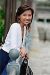 Femme accoudée à une balustrade, souriant à la caméra