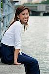 Woman sitting by river, smiling at camera