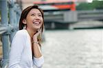 Woman sitting by river, smiling, looking up