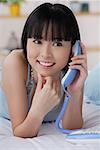 Young woman using telephone, smiling