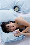 Junge Frau liegend auf dem Bett, Blick auf Handy