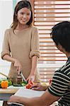 Woman chopping vegetables, looking at man in front of her