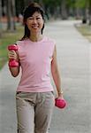 Mature woman using dumbbells in park