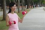 Femme mature, exercices avec des haltères dans le parc