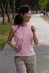 Mature woman walking in park, listening to MP3 player, smiling