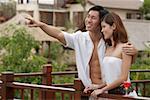 Couple debout côte à côte sur le balcon, l'homme pointant, embrassant la femme
