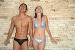 Couple in swimwear, eyes closed, water falling on them