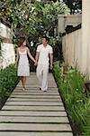 Couple marchant le long du chemin d'accès dans le jardin, main dans la main