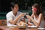 Couple sitting at outdoor table, toasting with glasses