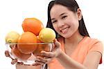 Young woman holding bowl of oranges and lemons towards camera