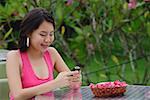 Young woman sitting at outdoor table, looking at mobile phone