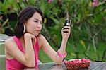 Young woman sitting at table outdoors, looking at mobile phone