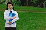 Young woman in school uniform, standing in park