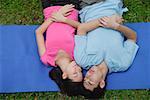 Couple in park, lying on mat, eyes closed