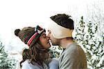 Young couple in winter clothes, kissing, side view