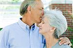 Mature man kissing wife's forehead, side view