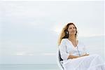 Woman sitting outdoors listening to headphones with eyes closed