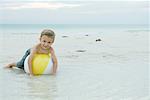 Little boy lying on beach ball, smiling at camera, full length