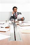 Businessman at Boardroom Table with Cellular Phone and Documents