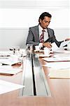 Businessman at Boardroom Table with Cellular Phone and Documents