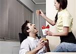 Office worker feeding her colleague at desk