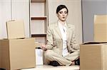 Businesswoman on desk among boxes meditating