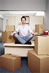 Businessman on desk among boxes meditating