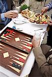 Closeup of businessmen at taverna with backgammon, appetizers, and ouzo