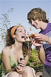 Male teenager feeding female teenager pizza