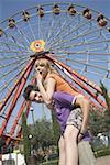 Teenage couple at Ferris wheel in amusement park