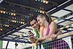 Couple d'adolescents avec téléphone cellulaire au parc d'attractions ride
