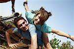 Teenage couple playing on piggy back in amusement park