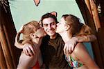 Two female teenagers kissing male teenager on cheek