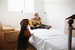 Girl with Guitar and Dog in Bedroom of New Home