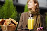 Gros plan de Croissants et de jus sur la Table avec une femme en arrière-plan