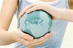 Woman holding globe in cupped hands, close-up, cropped view