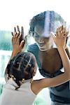 Mother and daughter making faces at each other through window, close-up