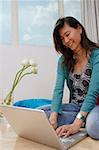 Young woman sitting on floor using laptop