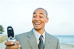 Businessman photographing self with cell phone at the beach, smiling